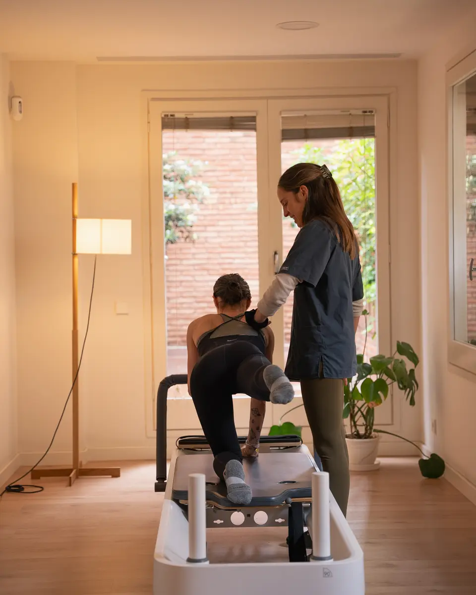 Fisioterapeuta guiando a una paciente en el reformer de pilates clínico