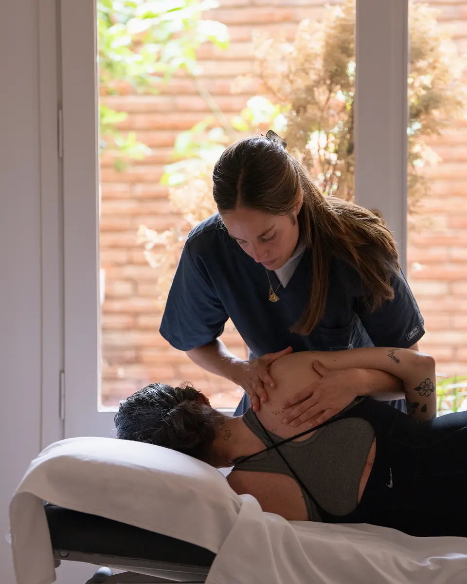 Fisioterapeuta tratando el hombro de una paciente en camilla